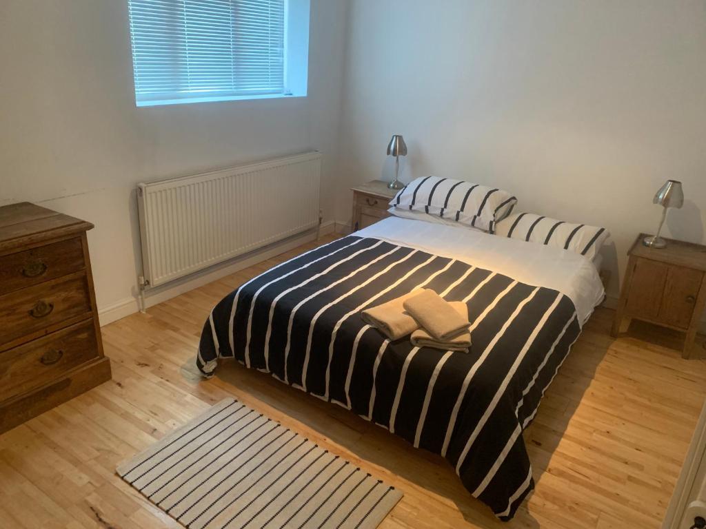 ein Schlafzimmer mit einem Bett mit einer schwarz-weißen gestreiften Decke in der Unterkunft Cozy 1 Bedroom Basement Flat in London