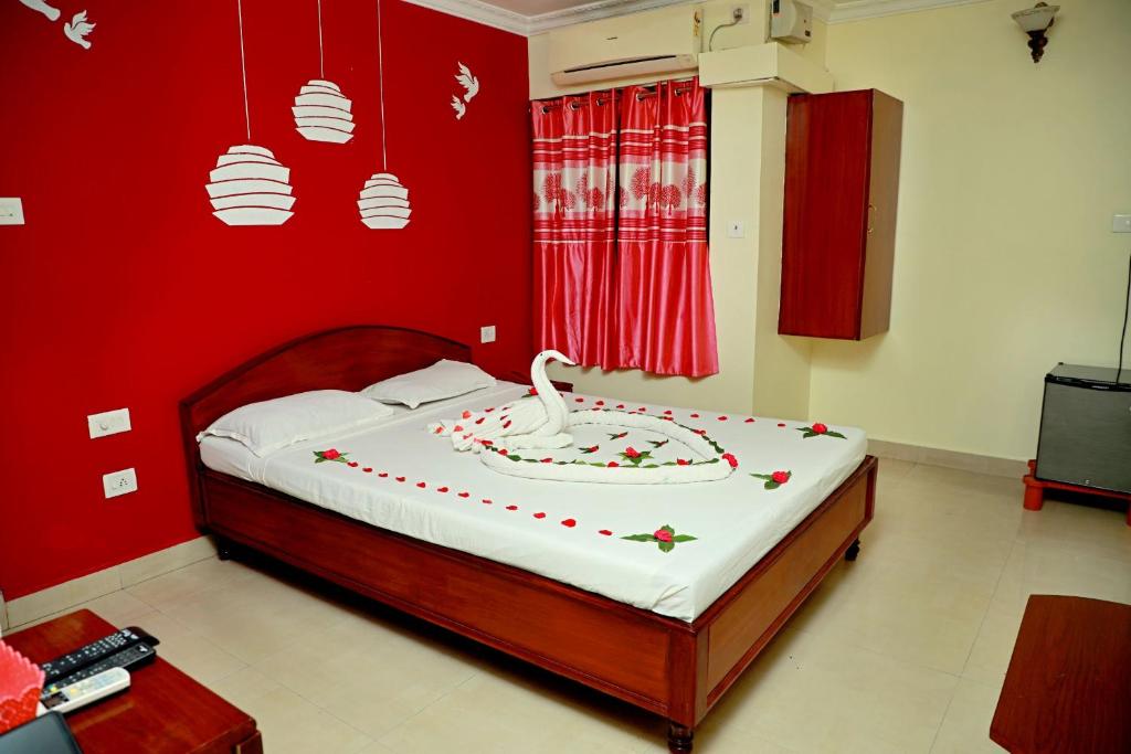 - une chambre rouge avec un lit recouvert d'un cygne blanc dans l'établissement Golden Sun Inn Hotel, à Pondichéry