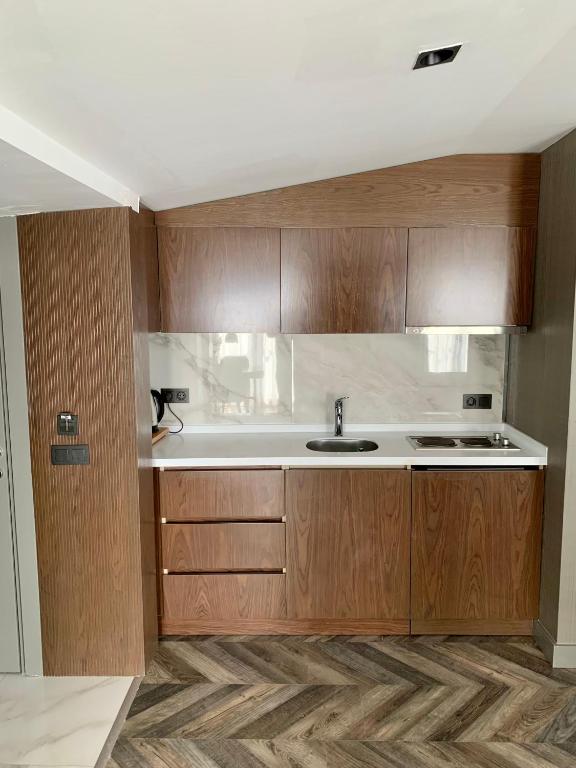 a kitchen with wooden cabinets and a sink at Istanbul Park Hotel in Tuzla