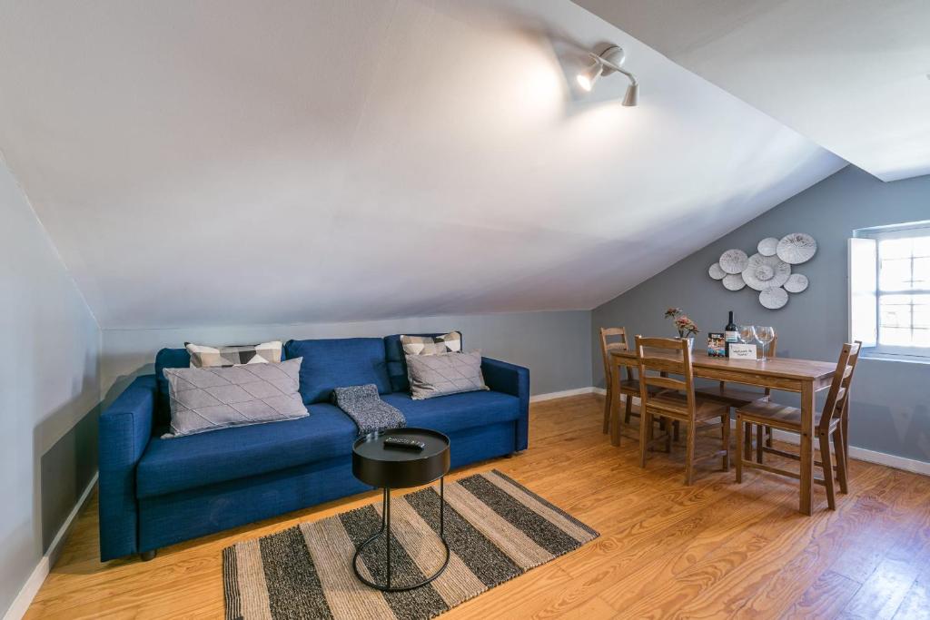 a living room with a blue couch and a table at GuestReady - Miragaia Rooftop in Porto