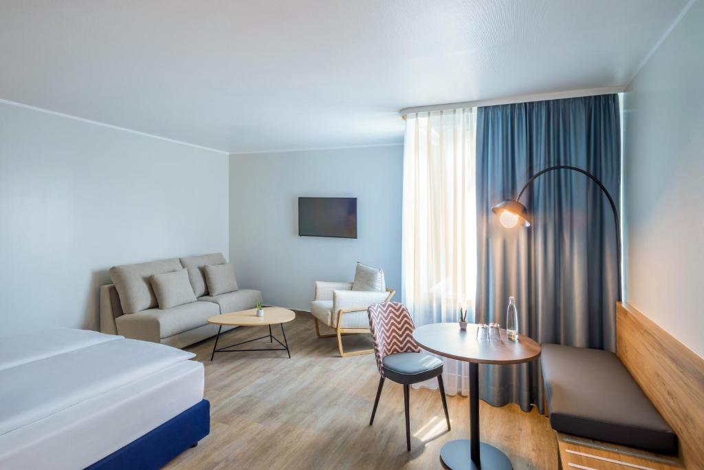 オーバーハウゼンにあるHotel Oberhausen Neue Mitte affiliated by Meliáのベッドとソファのあるホテルの部屋
