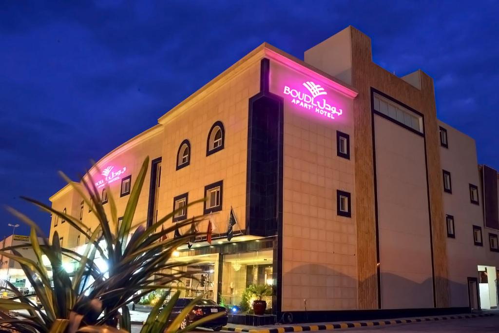 a building with a neon sign on the side of it at Boudl Majmaa in Al Majmaah