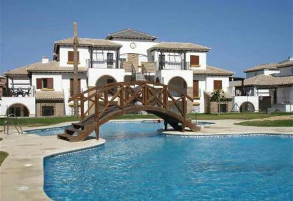 a wooden bridge over a pool in front of a house at Lovely Apartment in Vera Playa in Playas de Vera