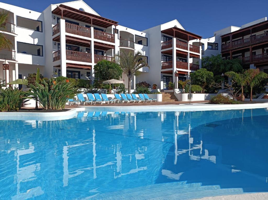 a swimming pool with chairs in front of a building at Nazaret Mansion in Costa Teguise