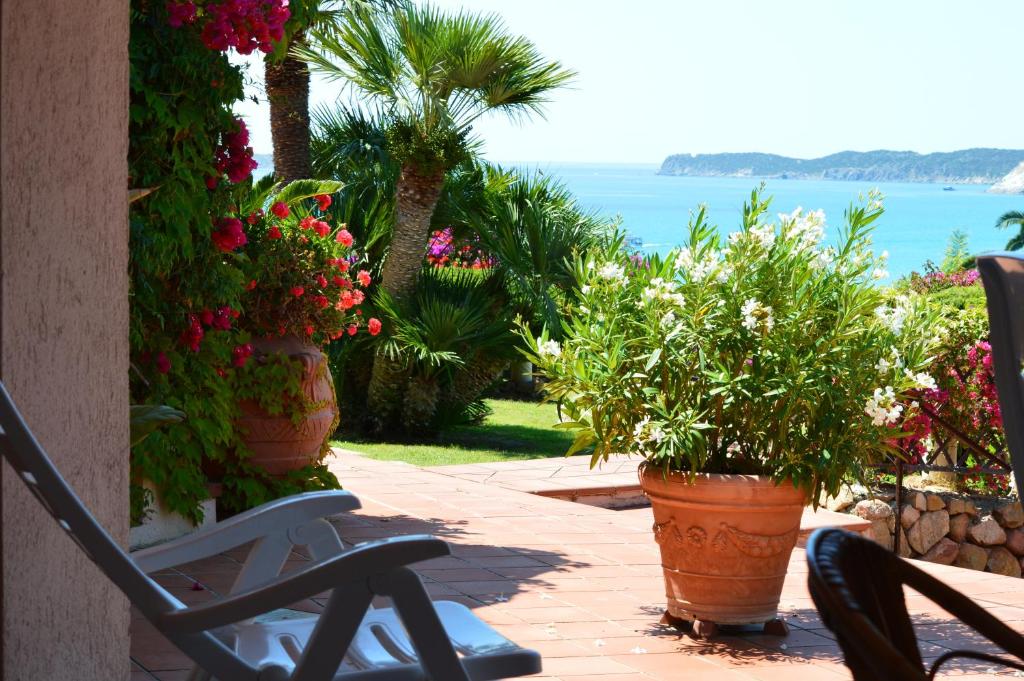 a patio with flowers and a chair and the ocean at Residence Fenicia in Villasimius