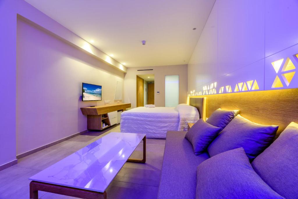 a hotel room with a purple couch and a bed at Seasons Hotel (Adults Only) in Ayia Napa