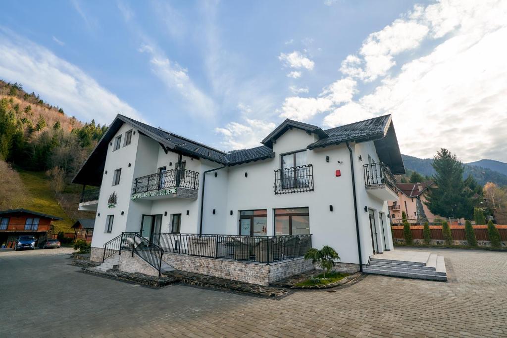 un edificio blanco con techo negro en Pensiunea Paradisul Verde, en Moisei