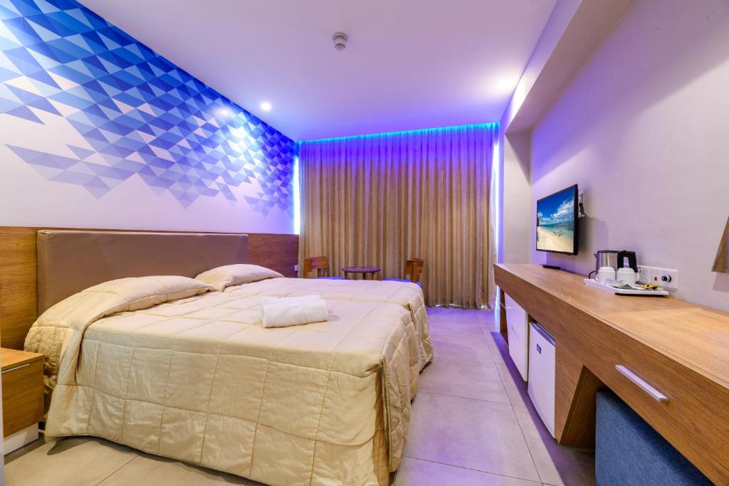 a hotel room with a large bed and a desk at Seasons Hotel (Adults Only) in Ayia Napa