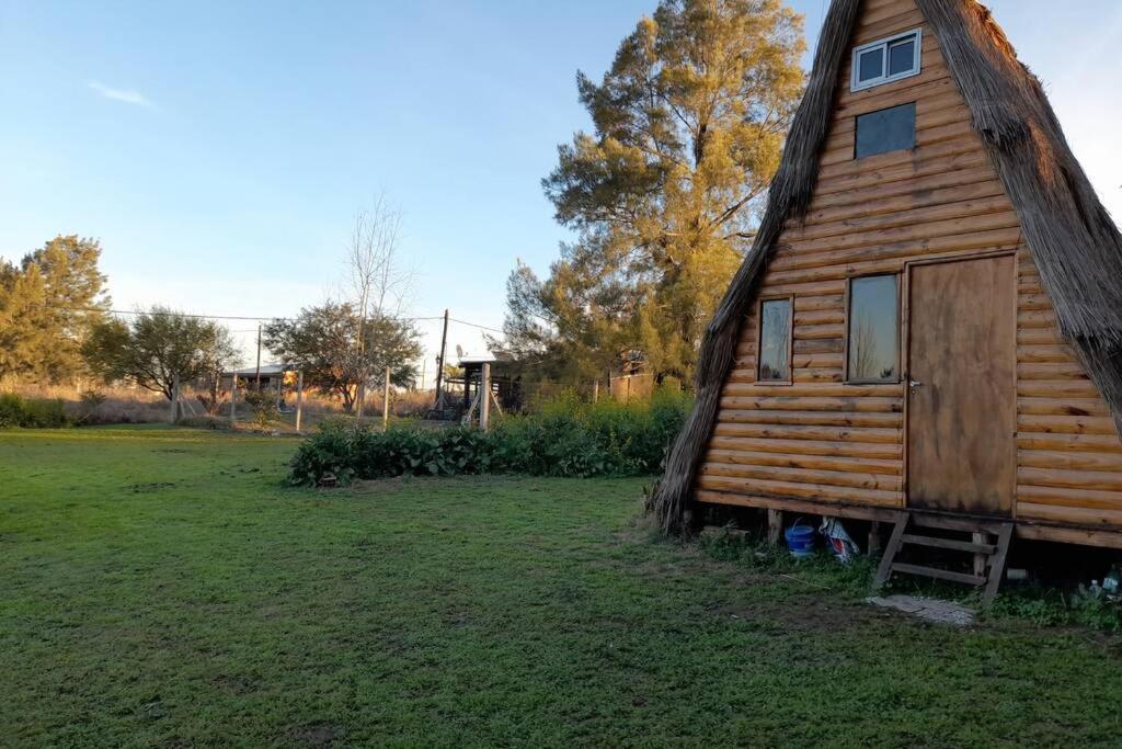 a small wooden house in a grass field at Cabaña Pirayú in Oliveros