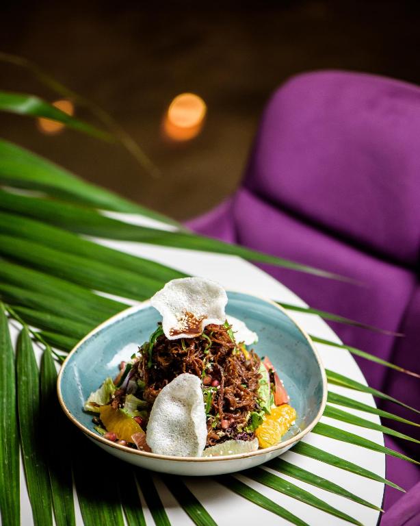 a plate of food on a table with a purple chair at Seasons Hotel (Adults Only) in Ayia Napa