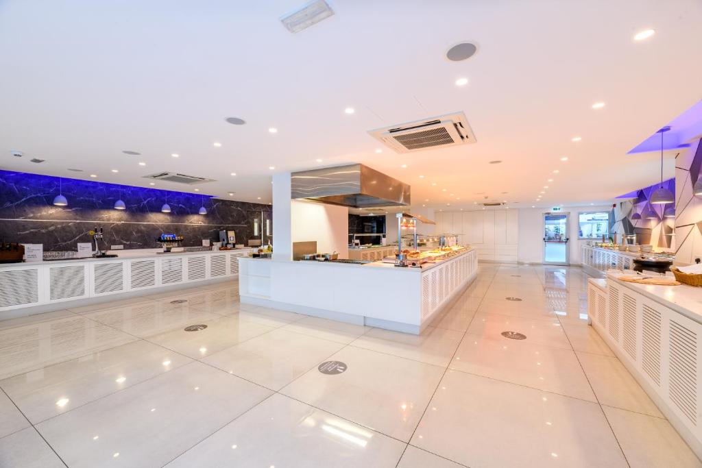 a restaurant with a white floor and a counter at Seasons Hotel (Adults Only) in Ayia Napa