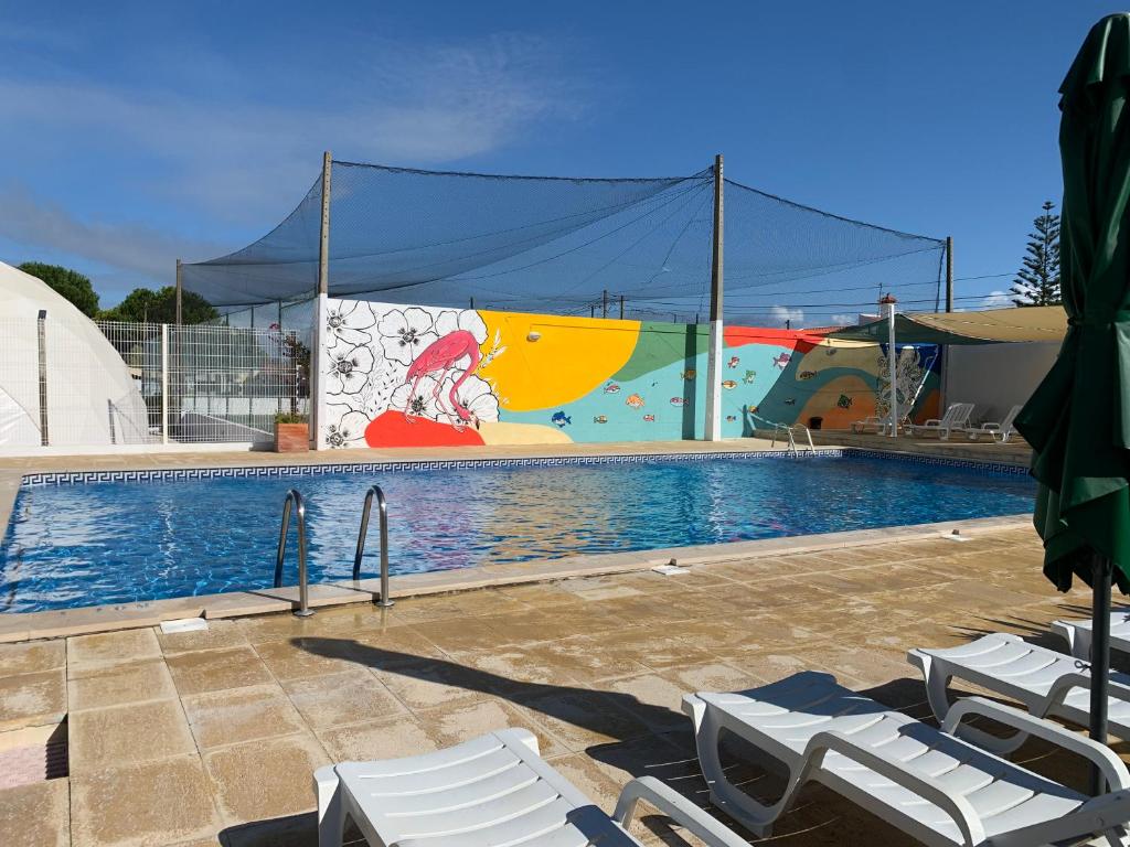 a swimming pool with lounge chairs and a mural at Solmeco Park in Aldeia do Meco