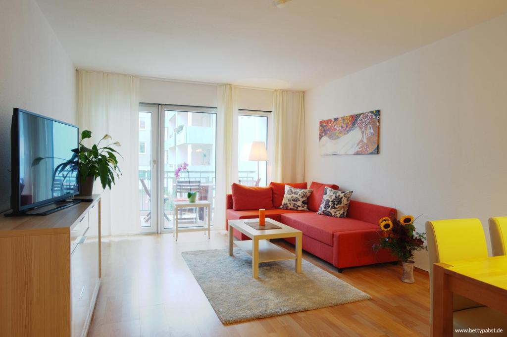 ein Wohnzimmer mit einem roten Sofa und einem TV in der Unterkunft Apartment an der Uni mit Tiefgarage und Loggia in Leipzig