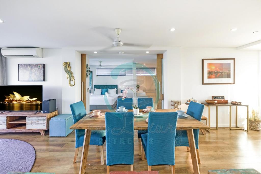 a dining room with a table and blue chairs at ZEN TOWERS PENTHOUSE Darwin's Exclusive Short Stays Holiday Home in Darwin