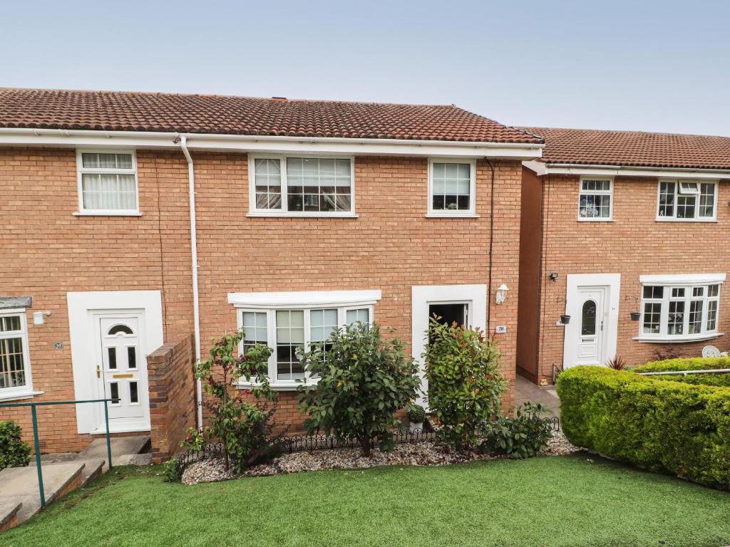 uma casa de tijolos com janelas brancas e um quintal em 28 Alwen Drive em Colwyn Bay