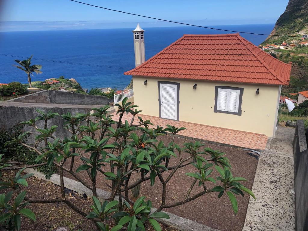 una piccola casa con un faro sullo sfondo di Panoramic Ocean View House a Faial