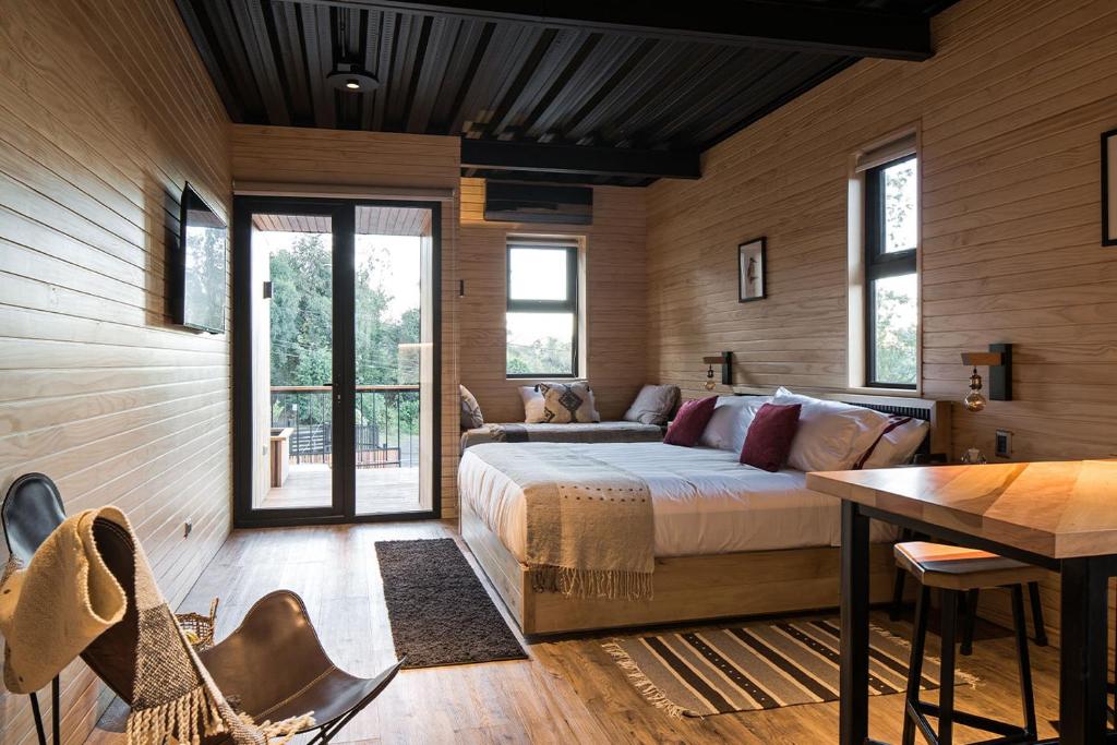 a bedroom with a bed and a table and chairs at Anoka Apart Hotel Boutique in Frutillar