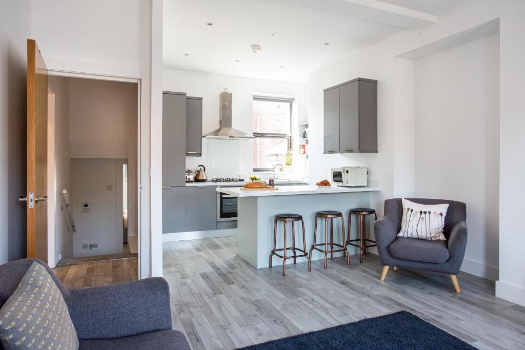 a kitchen and living room with a counter and chairs at Modern Luxury Apartment, Sleeps 6, Best Location in Belfast