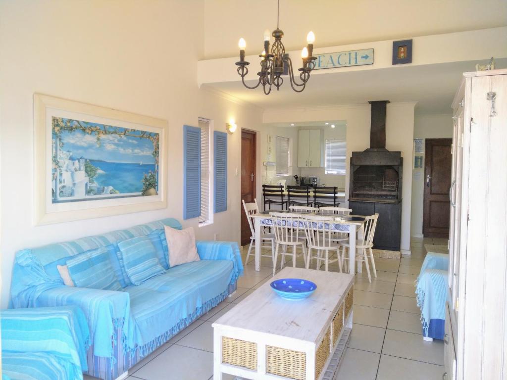 a living room with a blue couch and a table at Little Greece - Beach House Apartment by Mykonos in Langebaan