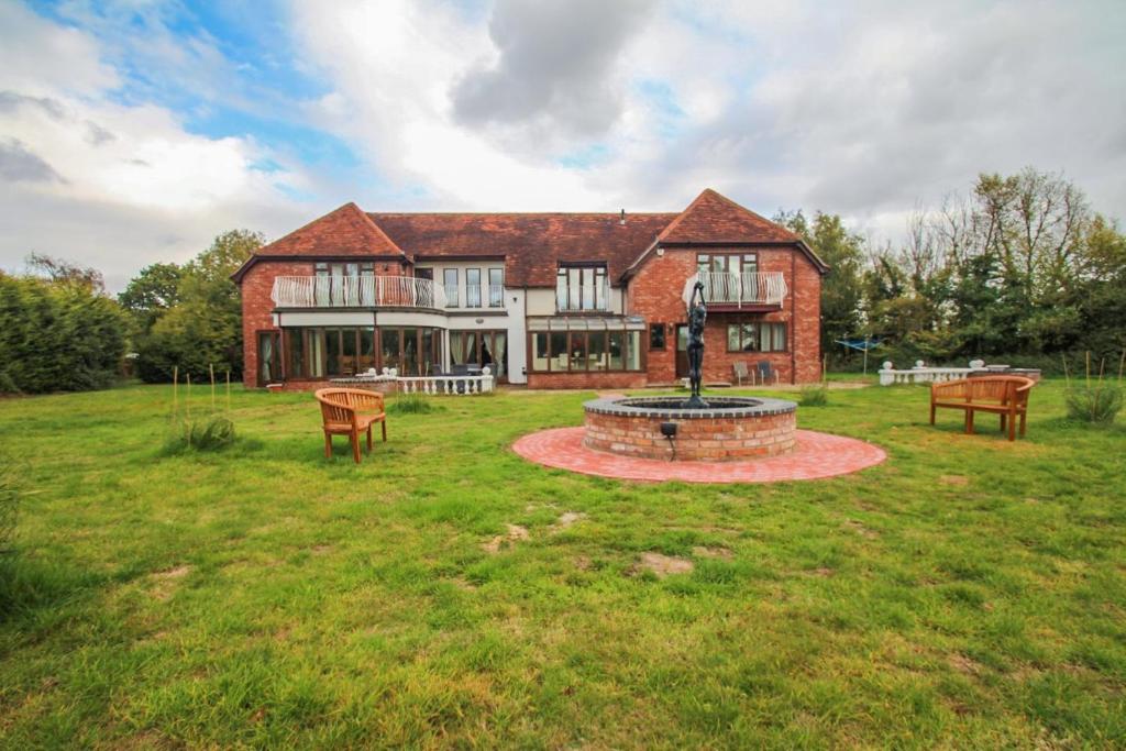 a large brick house with a fountain in the yard at Barnfields Retreat in Little Clacton
