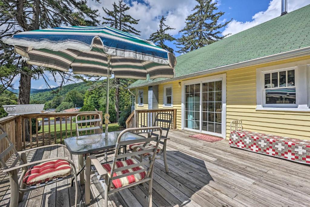 une table et des chaises sur une terrasse avec un parasol dans l'établissement Cozy Blue Ridge Cottage - Bike, Hike, and Fish!, à Bakersville