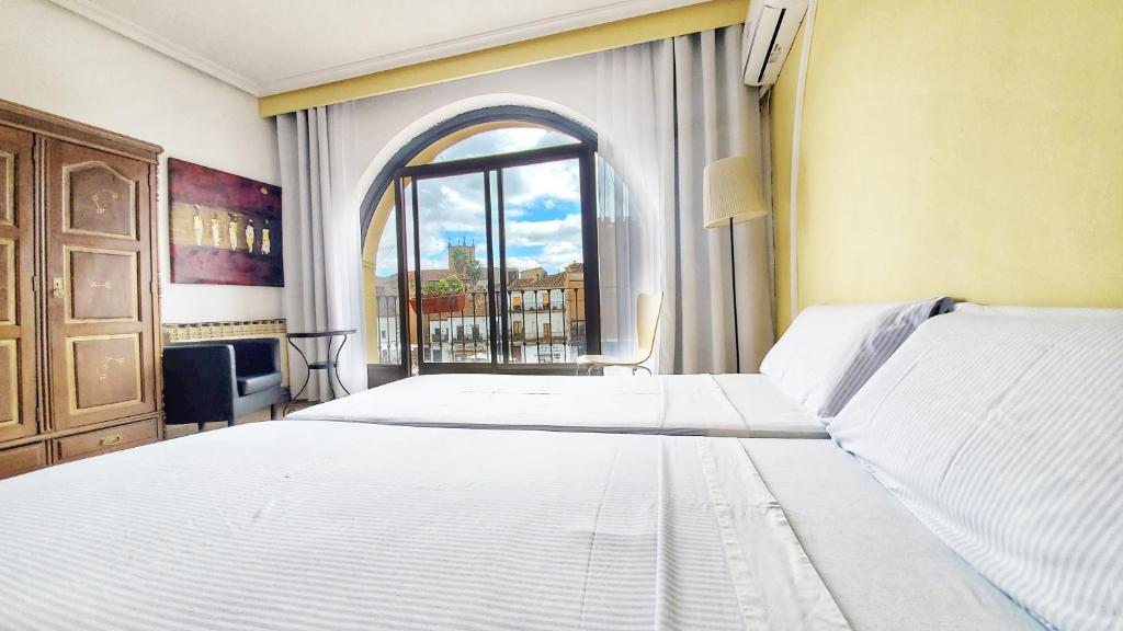 a bedroom with two white beds and a window at Hostal Martes Cáceres Plaza Mayor - Tercer piso SIN ascensor in Cáceres