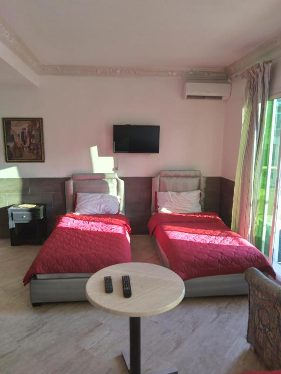 a room with two beds and a table and a tv at SINGAPOUR MAROC in Casablanca