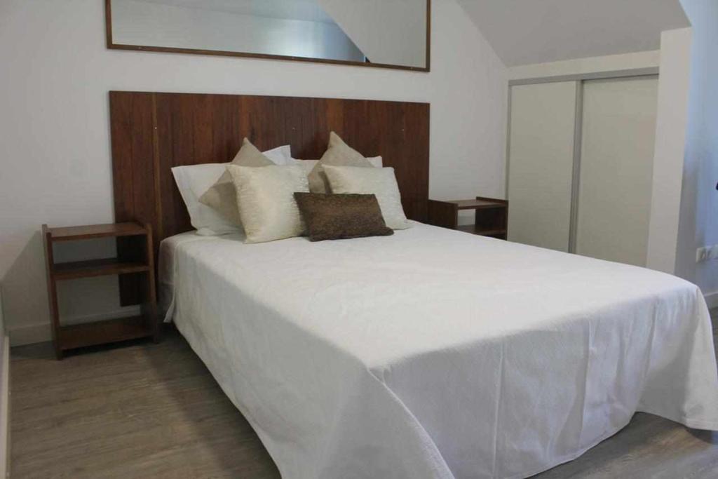 a bedroom with a large bed with white sheets and pillows at Casa da Ponte Casa familiar in Nordeste