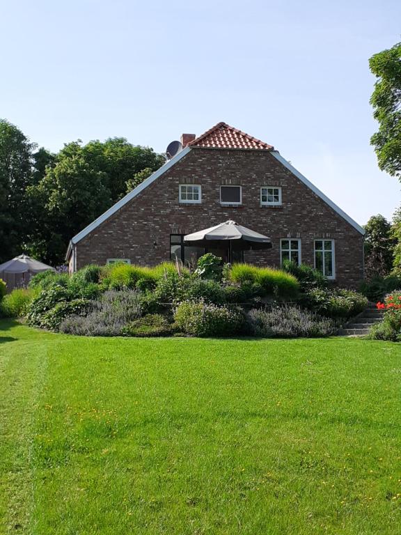 een stenen huis met een paraplu voor een tuin bij Pilsumer Warfthaus in Krummhörn