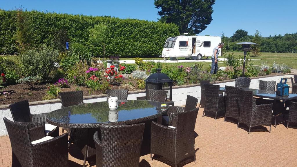 a patio with tables and chairs and a garden at Elysian Fields B&B in Helston