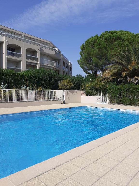 une grande piscine bleue devant un immeuble dans l'établissement T2 Bord de mer avec jardin et piscine, à Saint-Aygulf