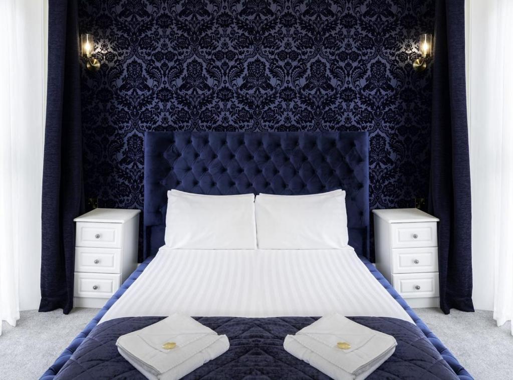 1 dormitorio con 1 cama grande y cabecero azul en The Pier Hotel, en Eastbourne