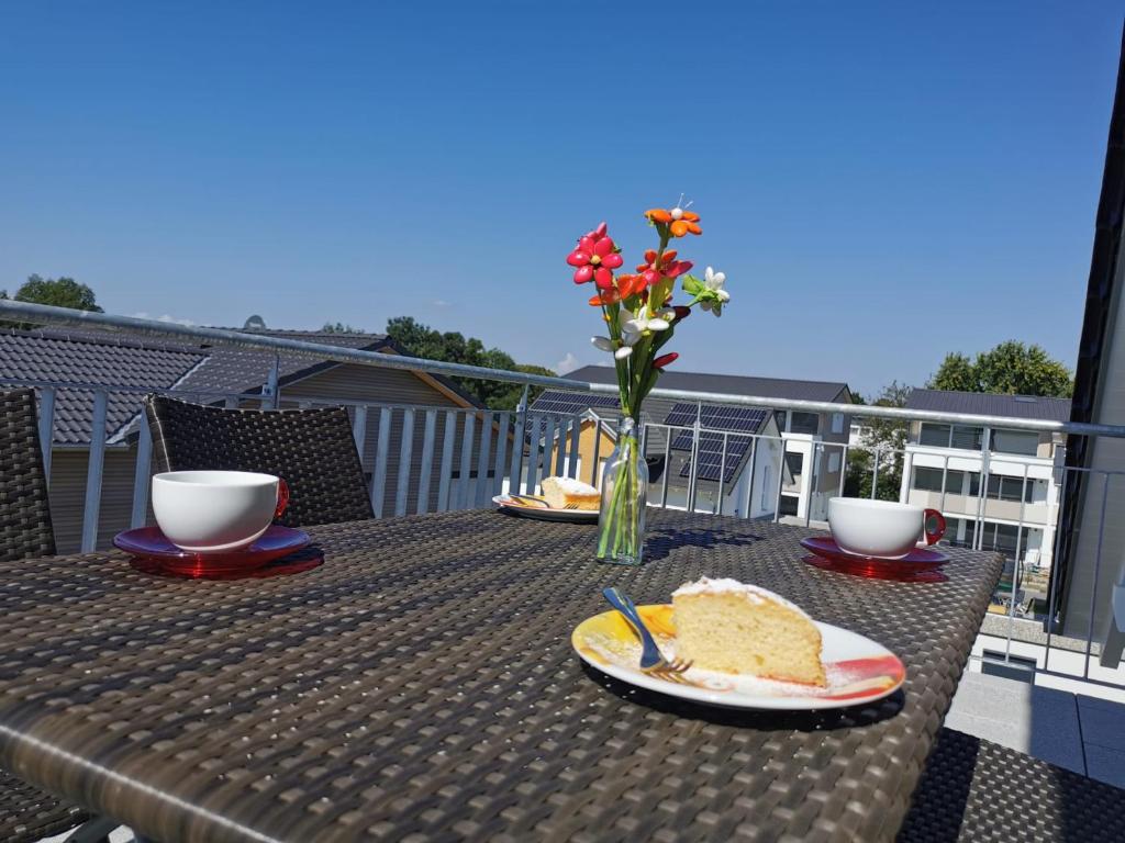 un tavolo con un piatto di torta e un vaso di fiori di Schlossseeapartment a Salem