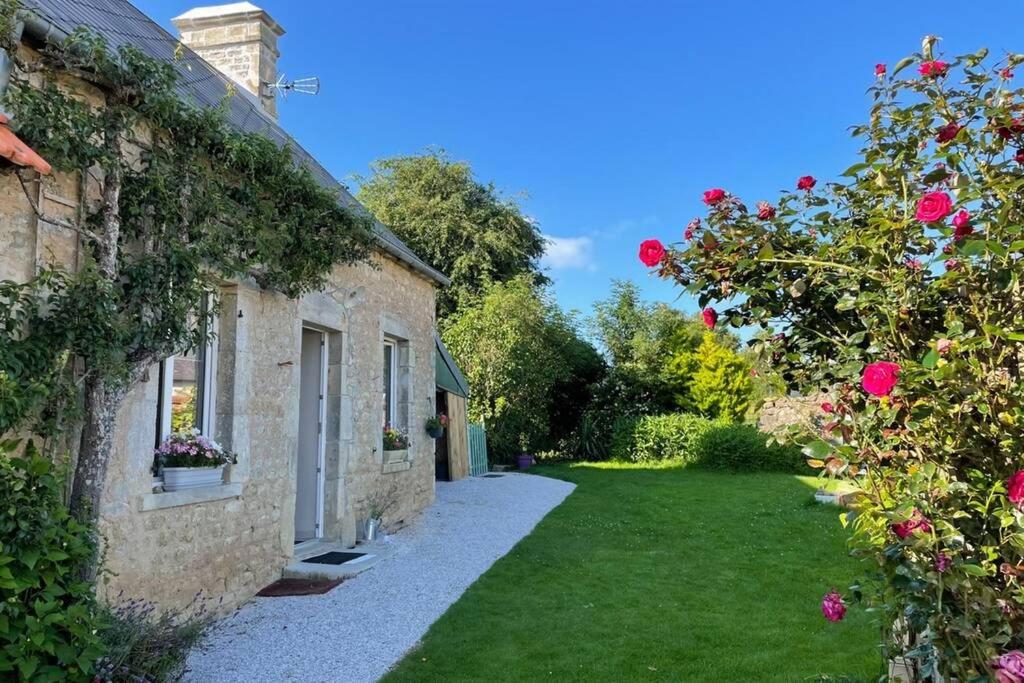an alley between two stone buildings with pink roses at Gîte en Cotentin in Étienville