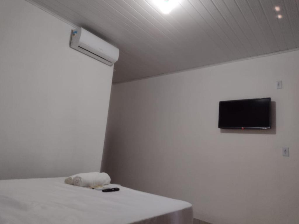 a room with a table and a tv on the ceiling at Pousada Enseada Quarta Praia in Morro de São Paulo