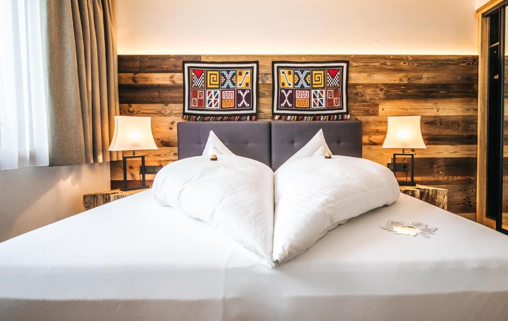 a bedroom with a white bed with two pillows at Hotel Andino in Sankt Anton am Arlberg