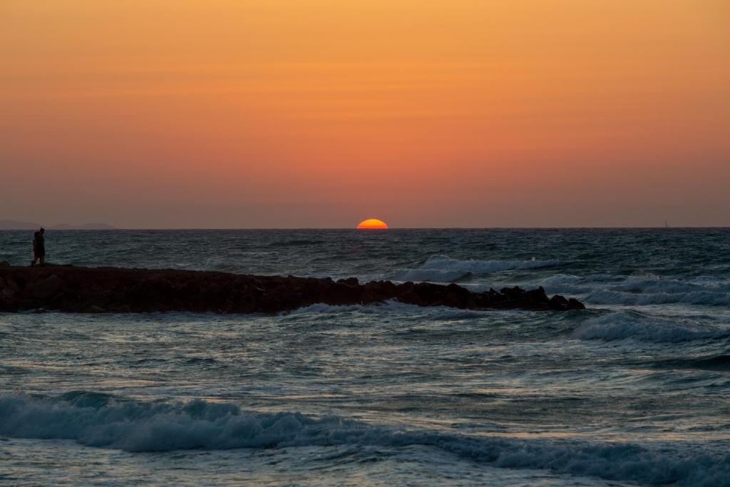 a person standing on a rock in the ocean at sunset at Kyma Seafront Suite by Estia in Kokkini Khanion