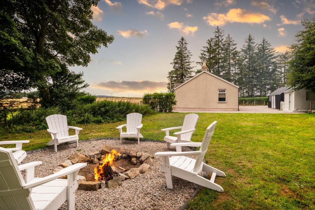 a group of white chairs around a fire pit at Stunning, Remodelled Cottage, Picturesque Location in Duncanston