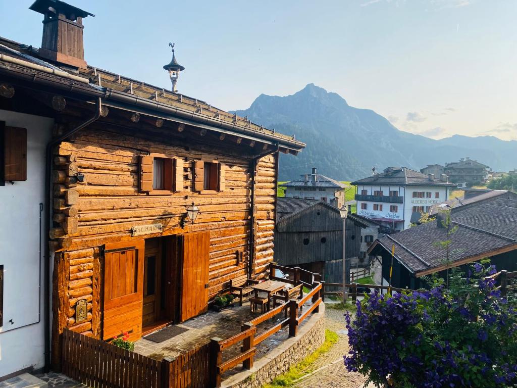 een houten huis met een berg op de achtergrond bij CHALET PA MAURAR Sauris in Sauris di Sopra