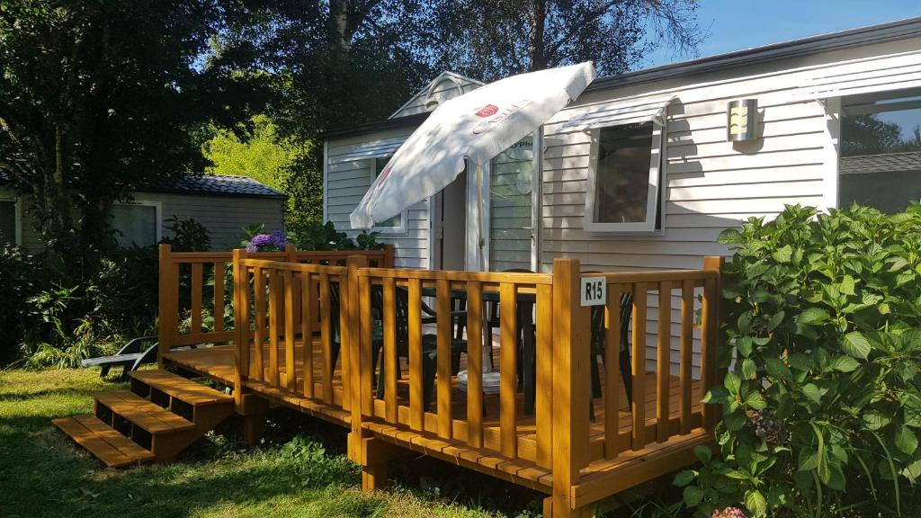 a wooden deck with an umbrella on a house at Royal Castel mobile home in Quimper
