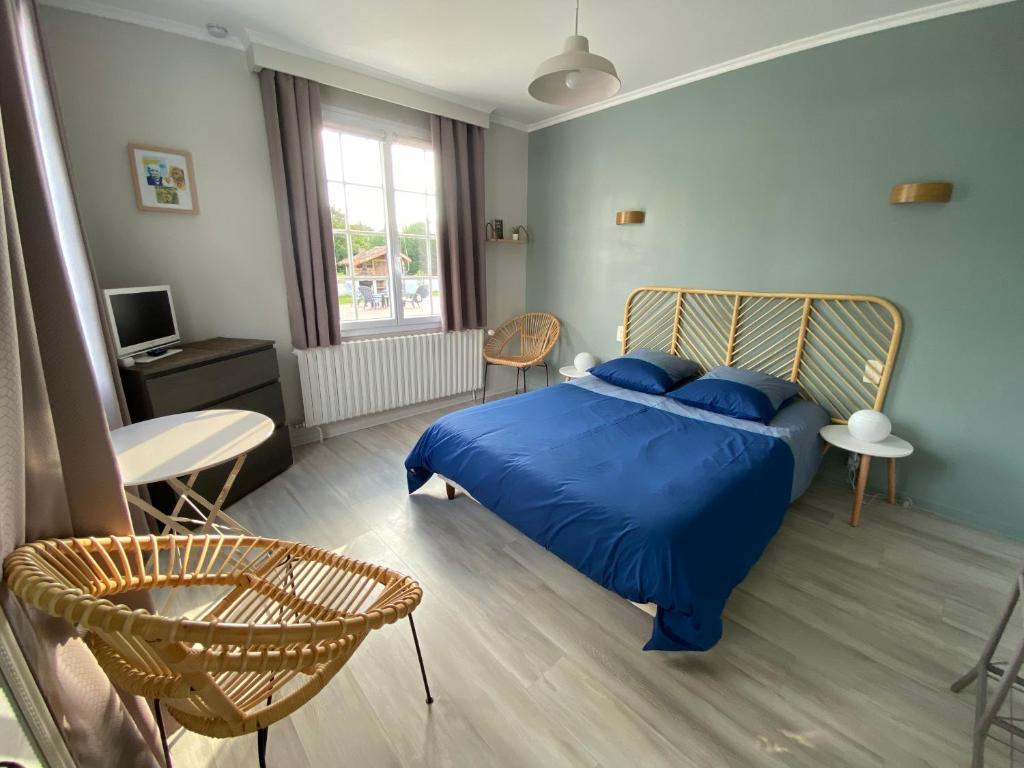 Schlafzimmer mit einem blauen Bett, einem Tisch und Stühlen in der Unterkunft Résidence Romaric in Jard-sur-Mer