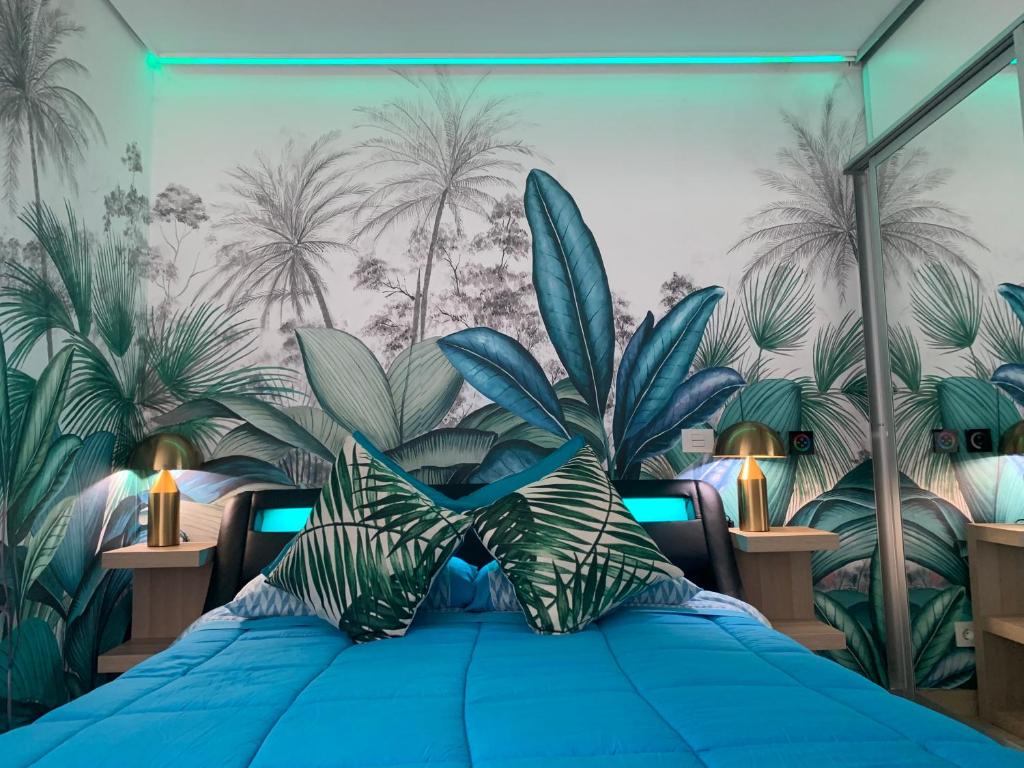 1 dormitorio con 1 cama azul y un mural de plantas en KOKA GOLD Samboors SUITE en Playa del Inglés