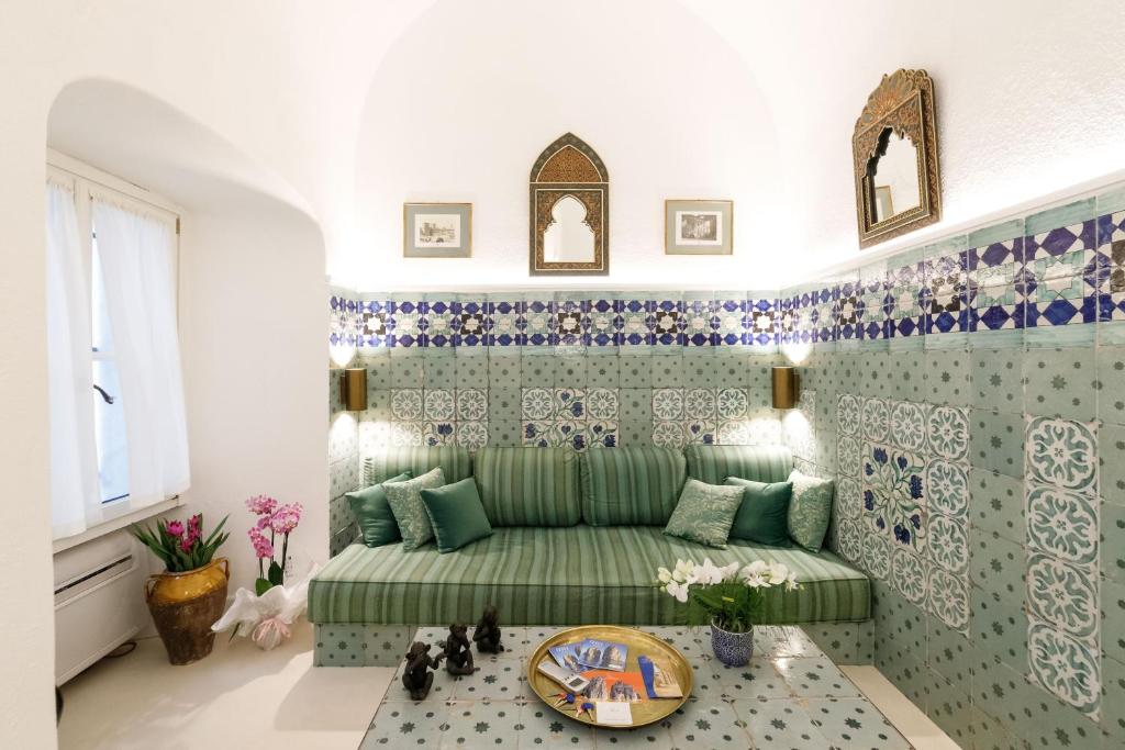 sala de estar con sofá verde y azulejos azules y blancos en Qasar Luxury Suite - in Capri's Piazzetta, en Capri