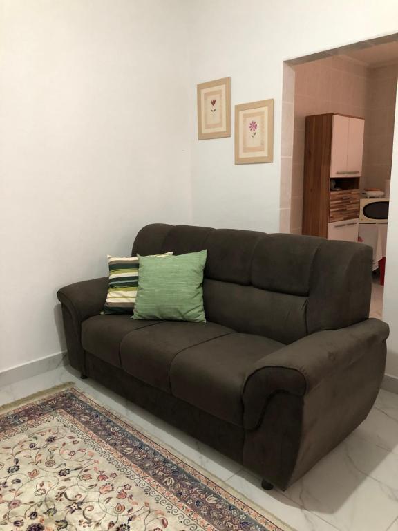 a brown couch in a living room with a rug at Casa Aconchego Guarujá in Guarujá