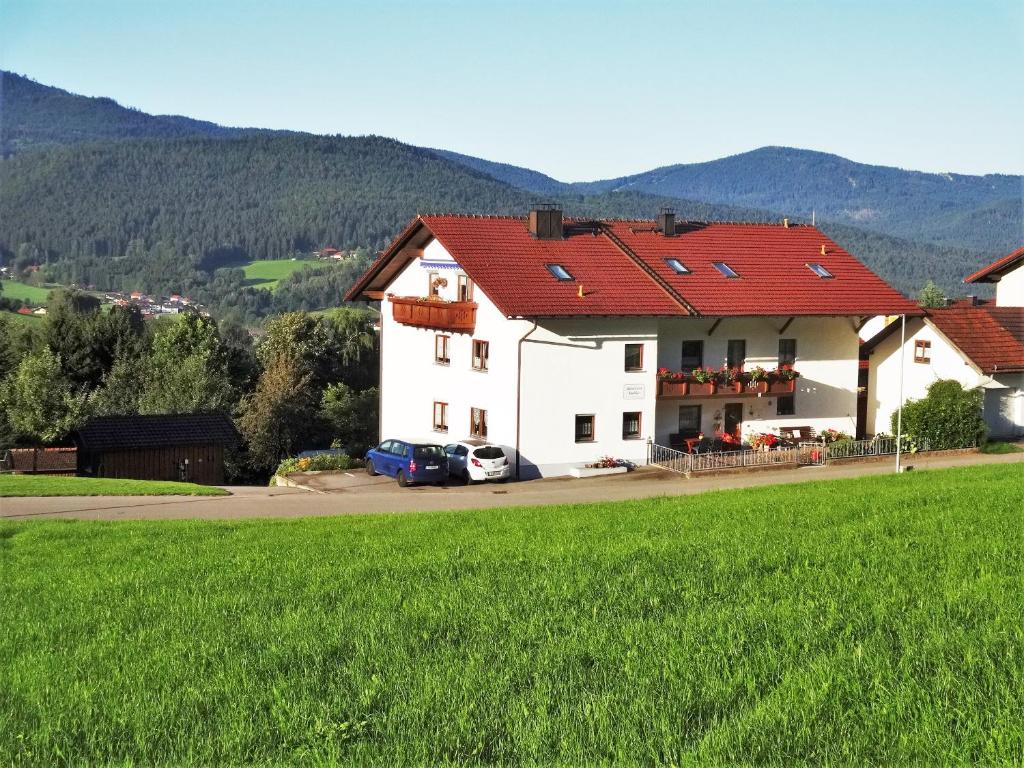 ein weißes Haus mit einem roten Dach und einem grünen Feld in der Unterkunft Gästehaus Kuchler in Lam