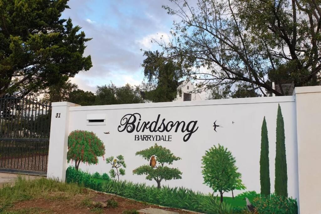 un cartello per un edificio con delle piante sopra di Birdsong Barrydale a Barrydale
