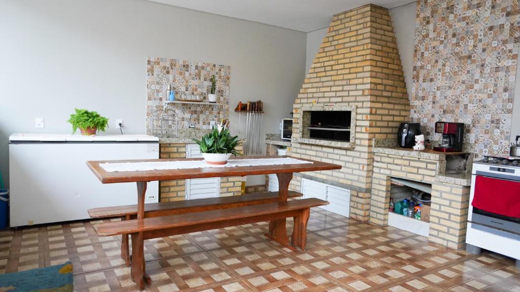 a kitchen with a table and a brick fireplace at Casas do Preto in Guarda do Embaú