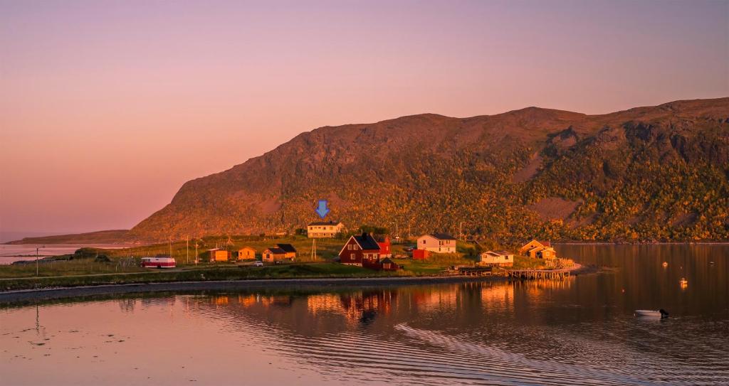 ein Dorf am Ufer eines Sees bei Sonnenuntergang in der Unterkunft Smørfjord Ferieleilighet in Russenes