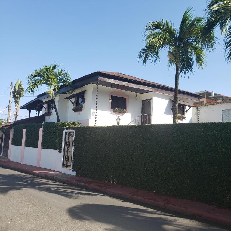 una casa blanca con palmeras y una valla en Lovely location , right downtown Puerto Plata, en San Felipe de Puerto Plata