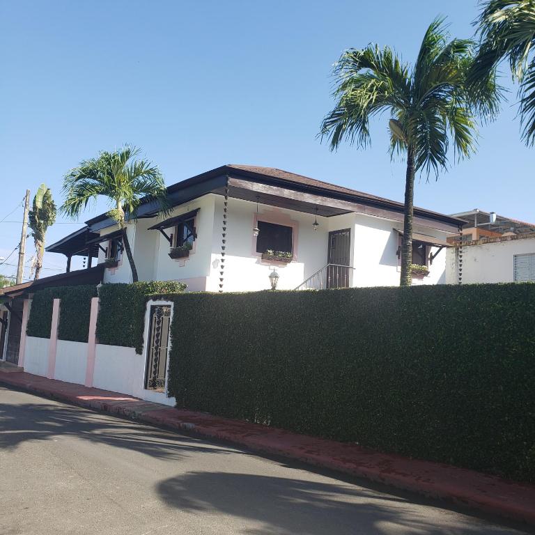 a white house with palm trees and a fence at Lovely location , right downtown Puerto Plata in San Felipe de Puerto Plata